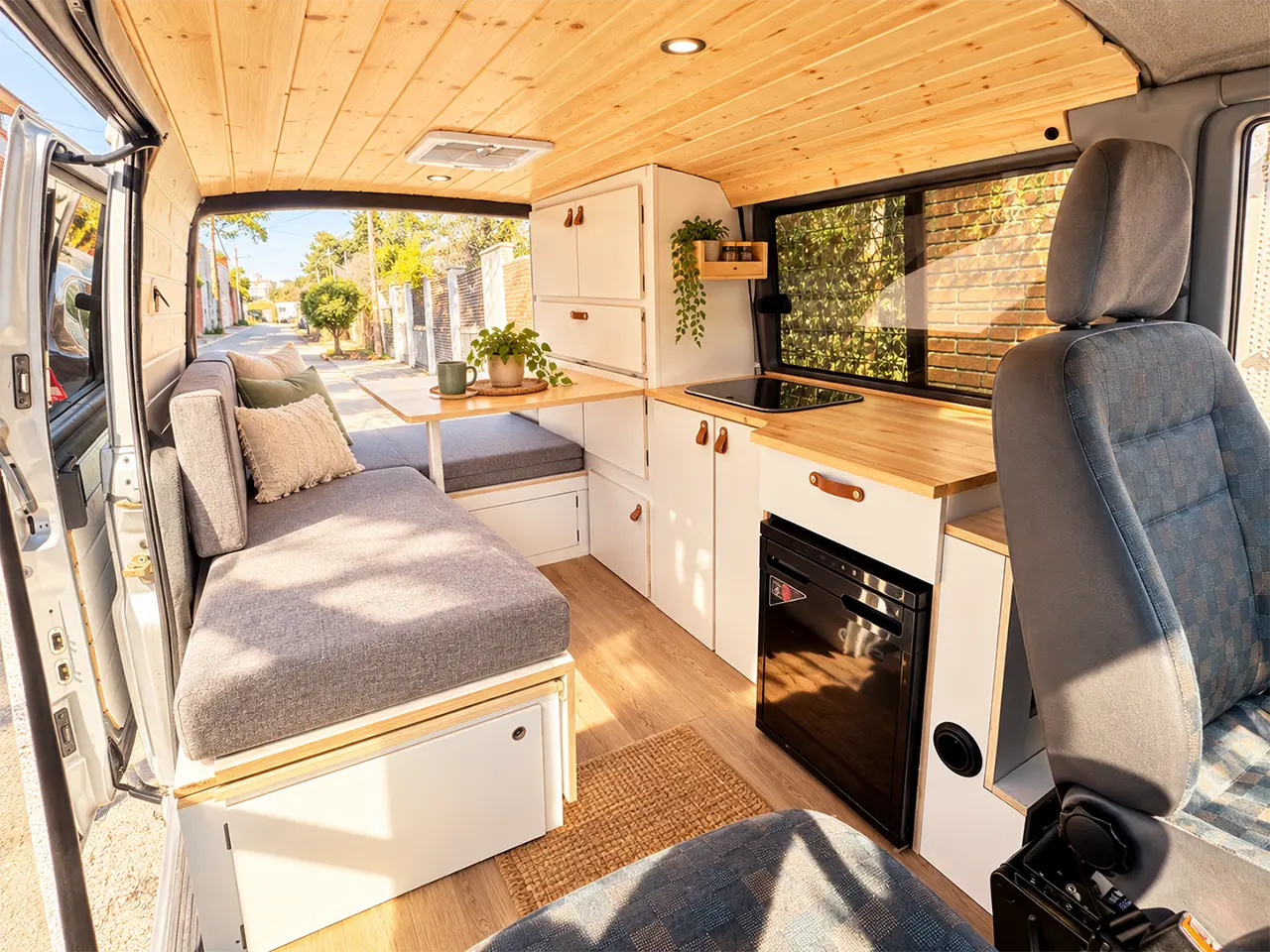 Zona de descanso de la Mercedes Vito camper con cama extensible y acabados de madera